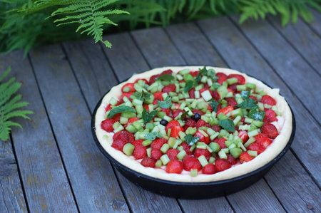 Half-finished tart with strawberry, rhubarb and peppermintの写真素材