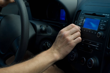 The driver is regulating some settings on car equipment