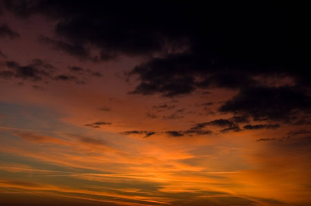 Contrast sky befor sunrise with black, grey, red and orange cloudsの写真素材