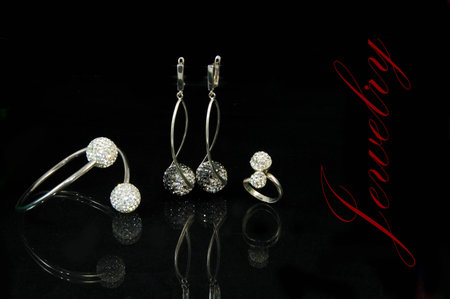 Silver set with earings, bracelet and ring with gems on the black background with reflectionの写真素材