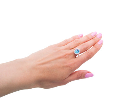 Very beautiful golden ring with blue gem - topaz and few diamonds  on woman's hand isolated on white backgroundの写真素材