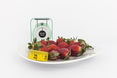 Strawberries in a plate with a weight scale isolated on white backgroundの写真素材