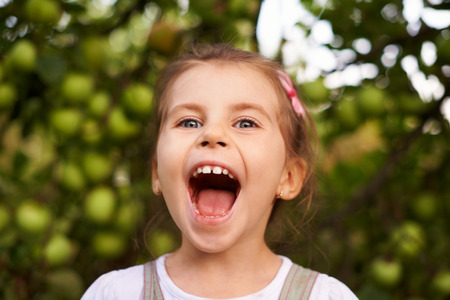 Portrait of a cute little girl making an excited face with her mouth wide openの写真素材