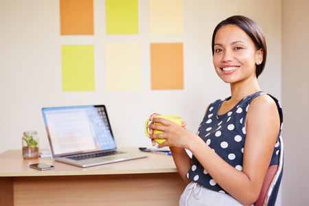 Portrait of a beautiful young professional woman sitting at her desk with her laptop openの写真素材