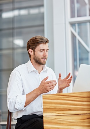 Young businessman engaged in a conversation on his laptop in a corporate settingの写真素材