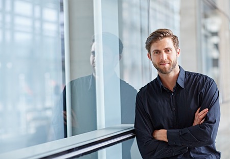 Portrait of a handsome executive looking positively at the camera in a modern settingの写真素材