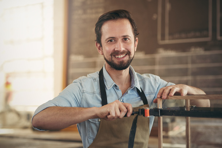 Portrait of a craftsman using a tool to manufacture a woodwork project in his workshop