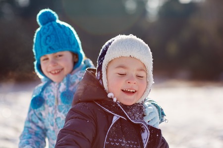 Candid shot of little boy and girl siblings outdoors on a sunny winter's dayの写真素材