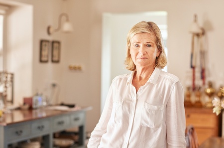Candid portrait of a senior woman looking at the camera with an expression of seriousness, while...