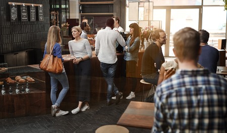 View through a window of a trendy modern coffee shop with some customers standing talking at the...