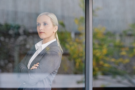 A young businesswoman looking through her office window