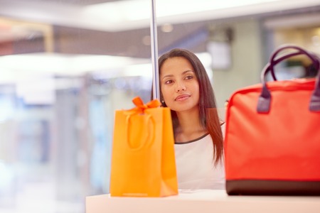 A young woman looking at a handbag through a shop window
