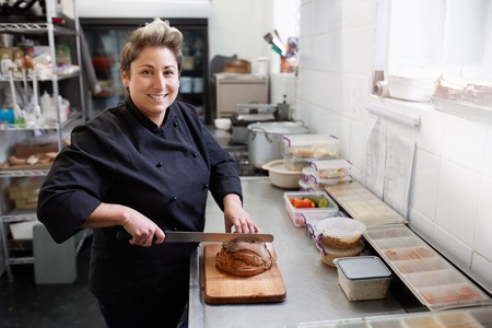 A female chef slicing bread in small kitchen
