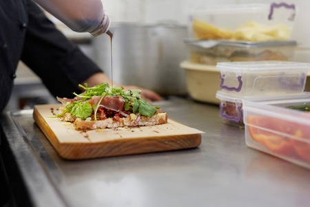 A female chef drizzling balsamic vinegar on an open sandwich