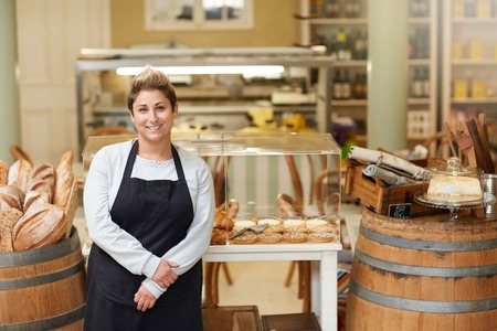 A young deli employee standing in front of the pastry display