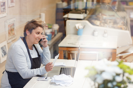 A female deli owner doing her taxes in her shopの写真素材