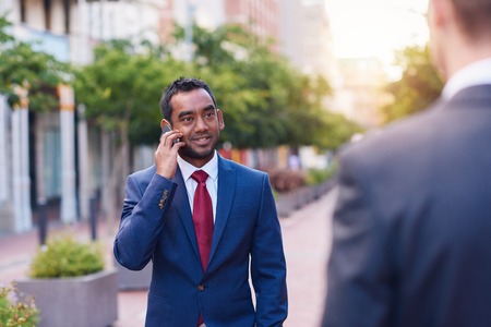 Businessman talking on a cellphone while walking in the city