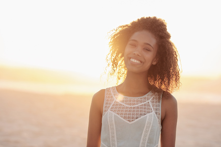 Portrait of a beautiful young woman standing on a beach at sunsetの写真素材