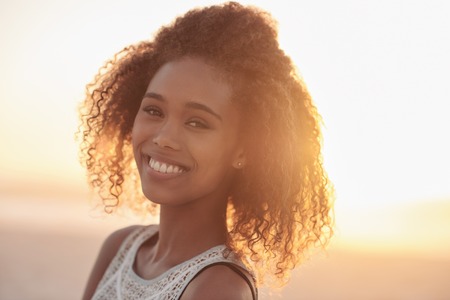 Portrait of a beautiful young woman standing on a beach at sunsetの写真素材