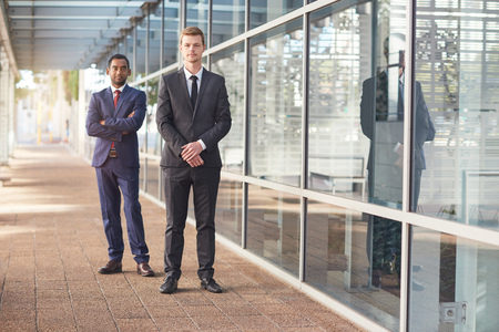 Portrait of two confident and successful businessmen standing in front of the glass windows of a modern office buildingの写真素材