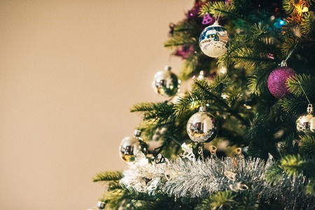 Closeup of tinsel and decorations hanging from the branches of a Christmas tree in a home during the festive seasonの写真素材