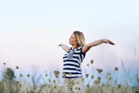 Young woman raising her arms to the blue skyの写真素材