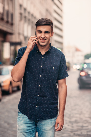 Smiling young man talking on a cellphone in the cityの写真素材