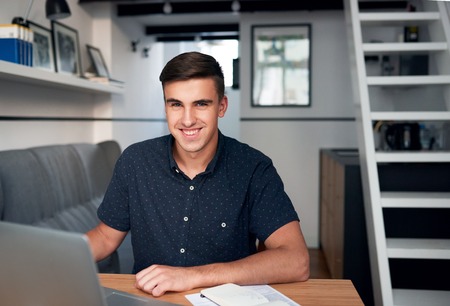 Handsome young man using a laptop at homeの写真素材