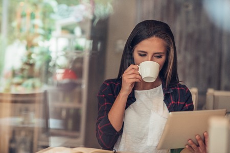 Young woman using a digital tablet at her favorite cafeの写真素材