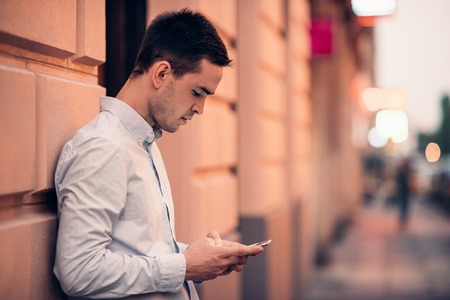 Handsome young man text messaging on a city streetの写真素材