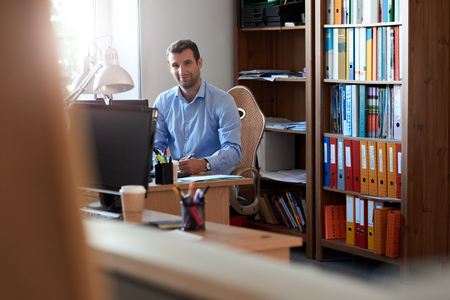 Smiling businessman working at his desk in an officeの写真素材