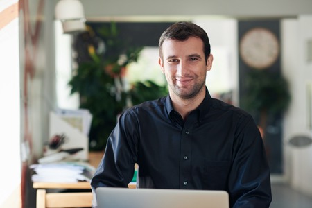 Successful businessman smiling and working on a laptop
