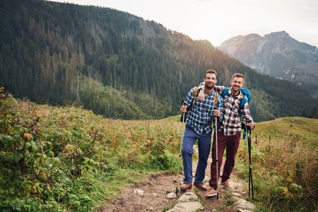 Smiling friends trekking together in the hillsの写真素材