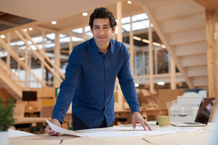 Positive young businessman sorting documents at an office deskの写真素材