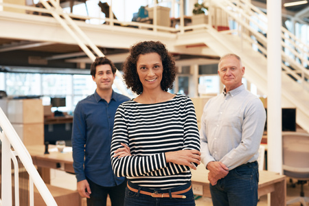 Smiling businesswoman in an office with coworkers standing behind herの写真素材