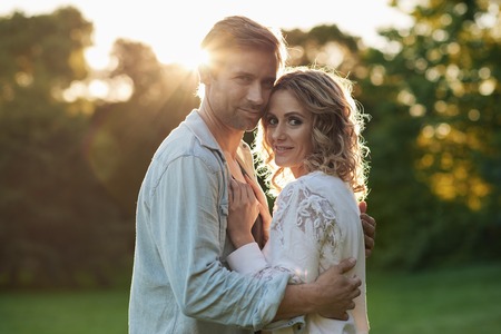 Romantic young couple standing in each others arms outsideの写真素材