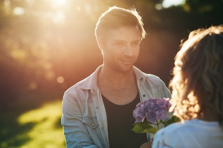 Young man giving his wife a bouquet of wild flowersの写真素材