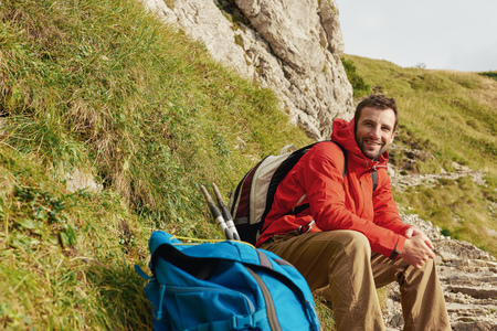 Smiling hiker sitting on a trail in the mountainsの写真素材