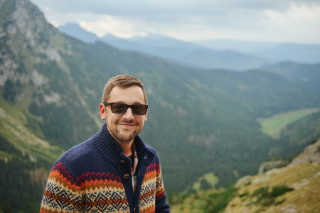 Smiling hiker standing in front of a majestic mountain landscape