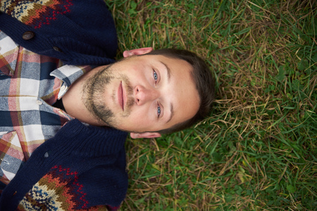 Smiling young man lying on grass in the great outdoorsの写真素材