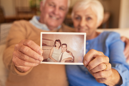 Hands of senior couple holding their youthful photo at homeの写真素材