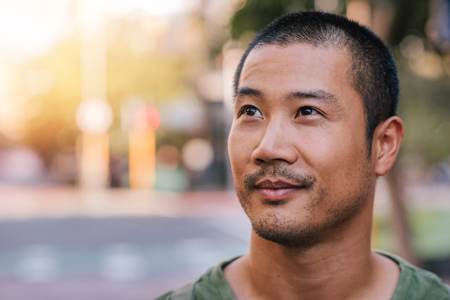 Handsome young Asian man standing on a city streetの写真素材