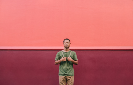 Cool young Asian man standing on a colorful city street