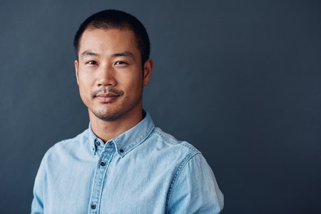 Confident and focused young Asian designer standing in an officeの写真素材
