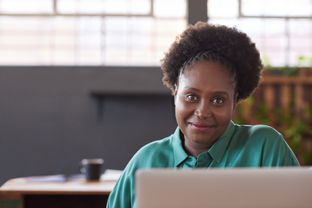 Smiling African businesswoman working on a laptop in an officeの写真素材