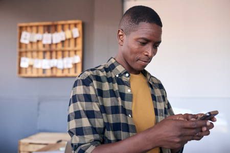 Young African businessman using a cellphone in an officeの写真素材