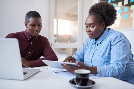 Young African businesspeople using technology together in an officeの写真素材