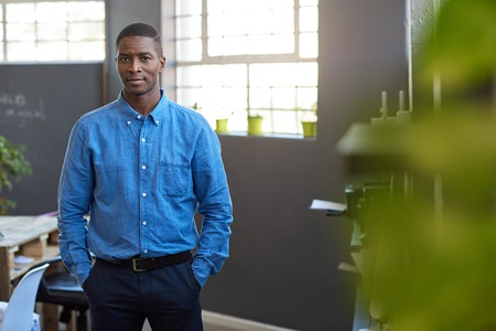 Focused African businessman standing in a modern officeの写真素材