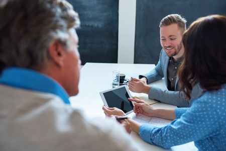 Smiling colleagues working with a digital tablet in an office