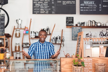Portrait of a friendly young African entrepreneur smiling while standing welcomingly behind the...